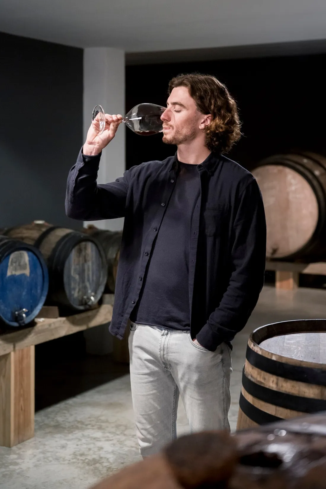 Le maître de chai goûte un vin au domaine, entre les barriques